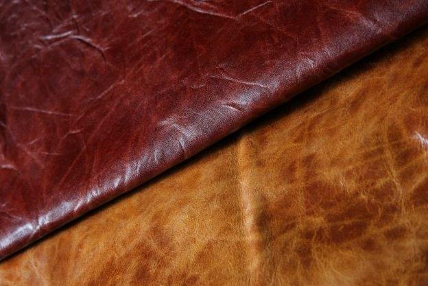 Zbliżenie na fałdowaną skórę w odcieniach brązu i bordo, ukazującą jej teksturę i naturalne przebarwienia. Widoczne delikatne refleksy światła.