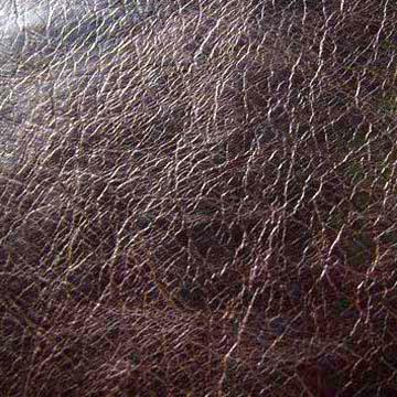 Brązowa skóra ekologiczna z delikatną fakturą, imitująca popękaną powierzchnię, widoczna z bliska pod kątem.