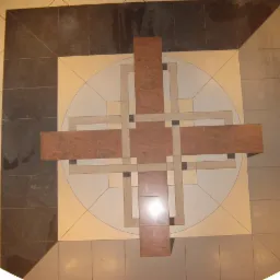 Wzorzysta podłoga z płytek w odcieniach beżu, brązu i szarości, z geometrycznym motywem krzyża na okrągłym tle, widoczna z góry.