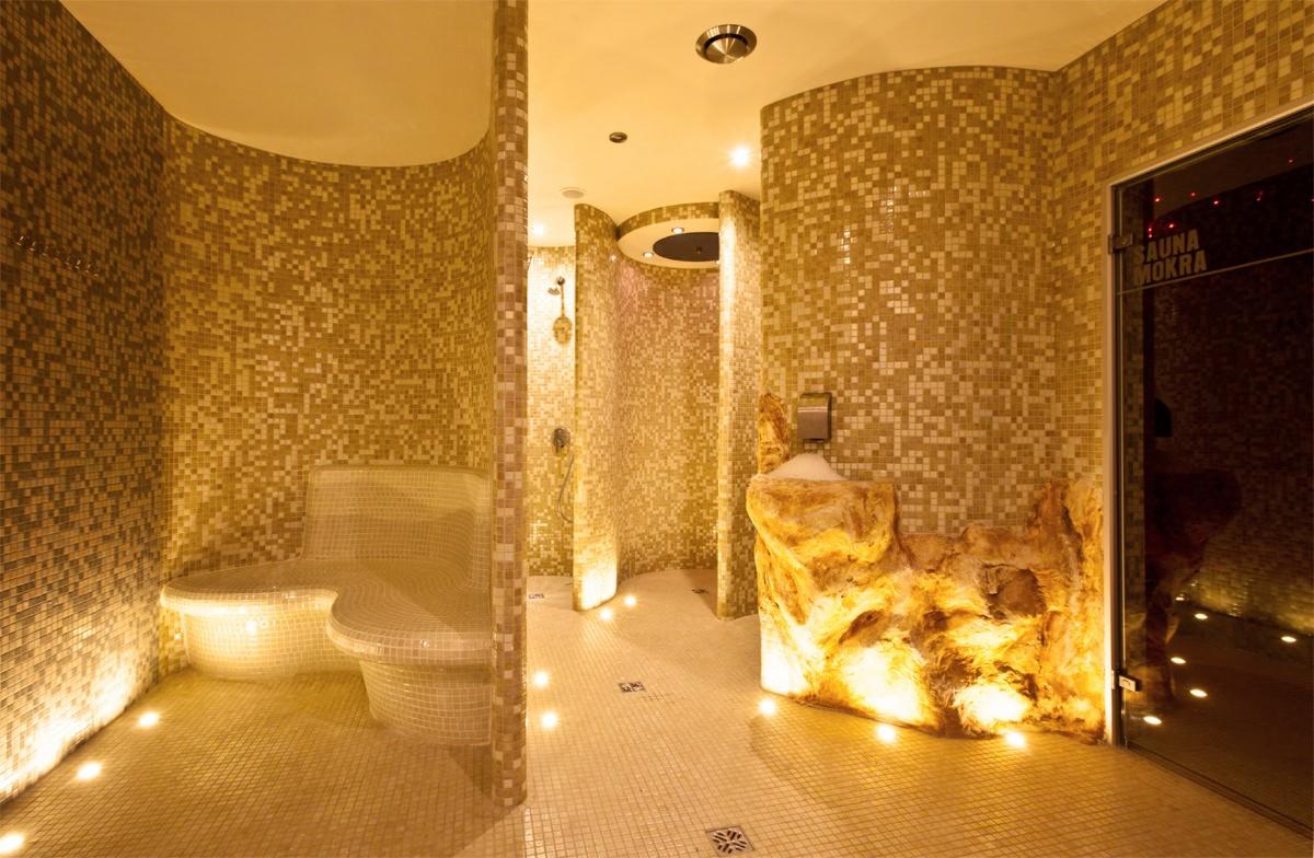 Mozaikowa sauna mokra z kamienną umywalką i subtelnym oświetleniem podłogowym. Szklane drzwi z napisem 'Sauna Mokra'.