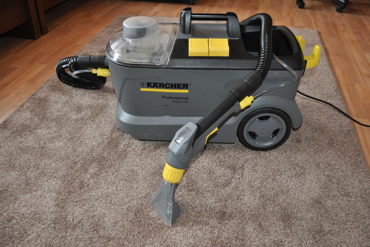 Profesjonalny odkurzacz piorący Kärcher Puzzi 10/1 na brązowym dywanie z długim włosiem, widoczne detale konstrukcyjne i elementy sterujące w kolorze żółtym.