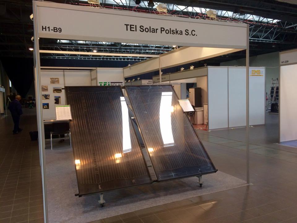 Stoisko TEI Solar Polska S.C. prezentuje dwa kolektory słoneczne na kółkach podczas targów. Widoczne oświetlenie halogenowe, metalowa konstrukcja i otoczenie hali.