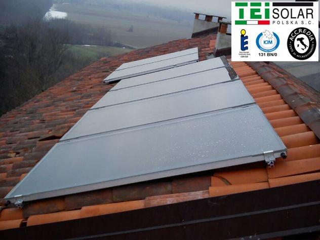 Instalacja solarna na dachu z czerwonej dachówki, widoczne krople wody na panelach, logo TEI Solar w prawym górnym rogu.