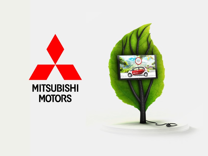 Ekran z prezentacją samochodu Mitsubishi umieszczony na grafice liścia z drogami, obok logo Mitsubishi Motors na białym tle.