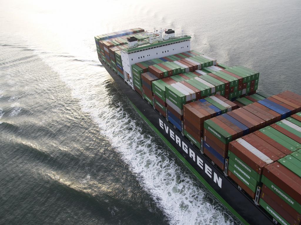 Kontenerowiec Evergreen płynie po wodzie, widok z góry. Widoczne rzędy kolorowych kontenerów i wzburzona woda za statkiem.