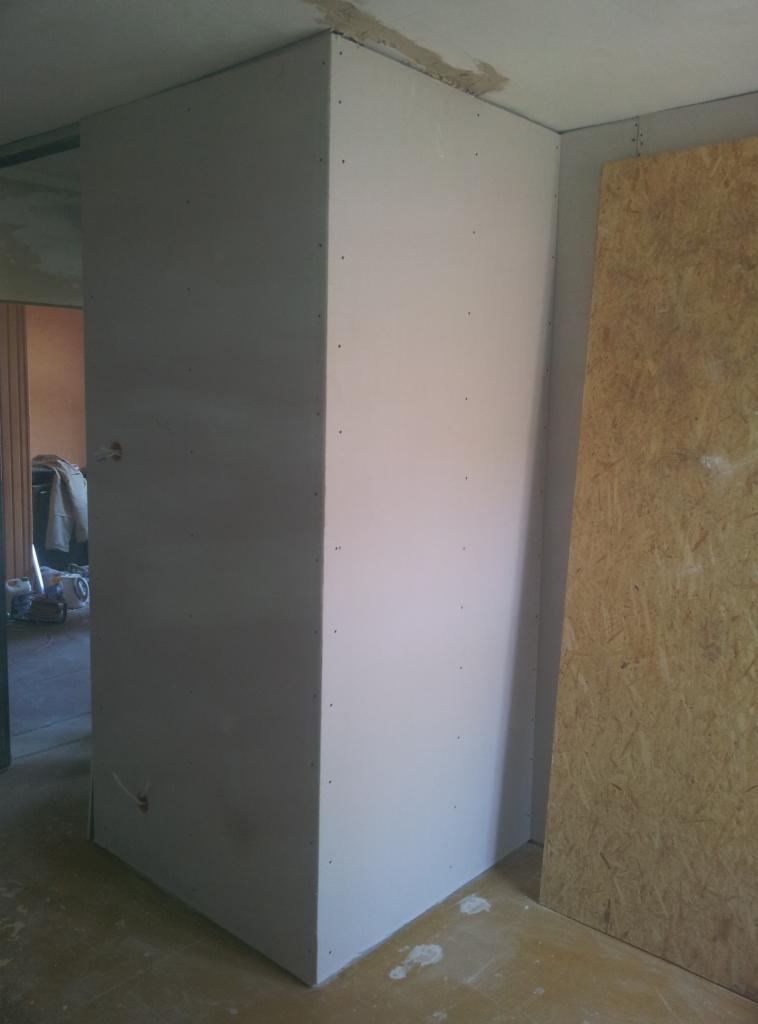 Wnętrze w trakcie prac wykończeniowych: narożnik z płyt gipsowo-kartonowych, widoczne ślady po wkrętach, płyta OSB na ścianie, przygotowanie do dalszych etapów prac.