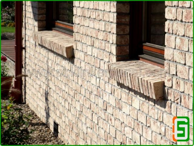 Elewacja z cegły klinkierowej z parapetami. Widoczny fragment ściany z oknami i detalami wykończenia, ukazujący fakturę i kolorystykę materiału.