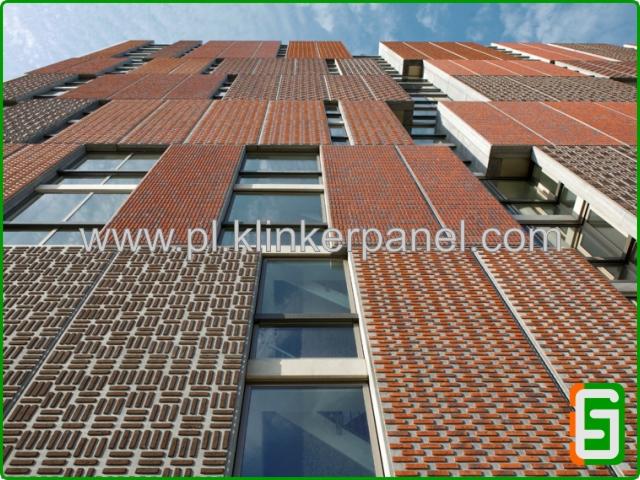 Elewacja budynku z paneli klinkierowych w odcieniach czerwieni i brązu, ułożonych w geometryczne wzory, widok z dołu, okna z metalowymi ramami.