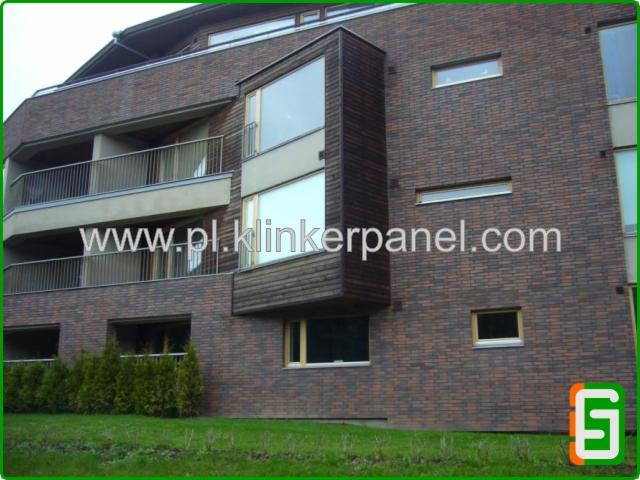 Budynek wielorodzinny z elewacją z paneli klinkierowych w odcieniach brązu i grafitu, balkony z metalowymi barierkami, część elewacji wykończona drewnem.