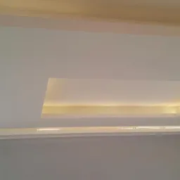 Podwieszany sufit z oświetleniem LED w ciepłej tonacji, tworzący geometryczne wzory na białej powierzchni.