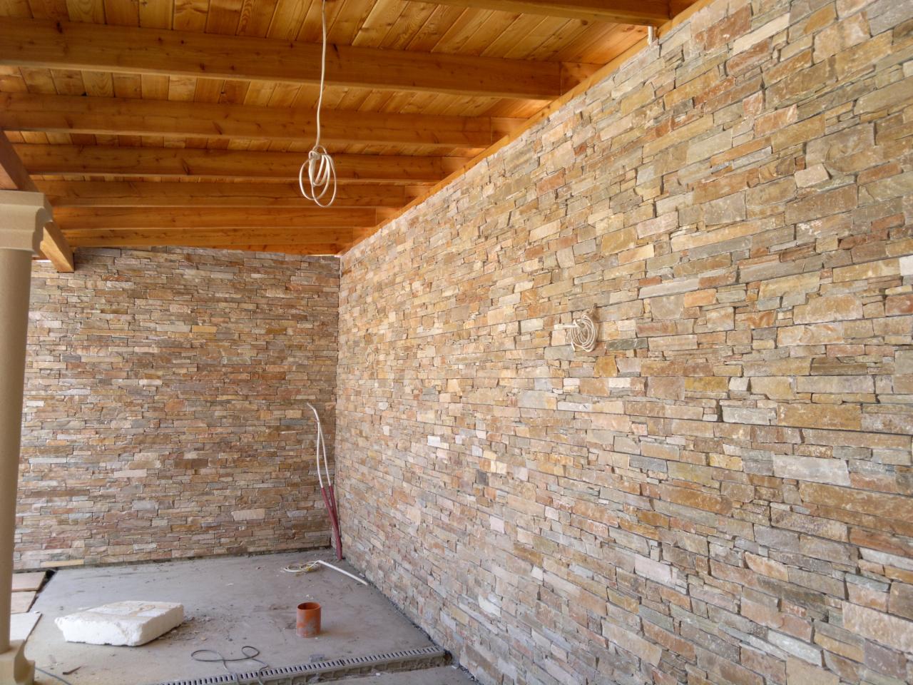 Kamienna elewacja wewnętrzna z drewnianym sufitem i widocznymi kablami. Realizacja w odcieniach beżu i brązu, z detalami wykończeniowymi w tle.