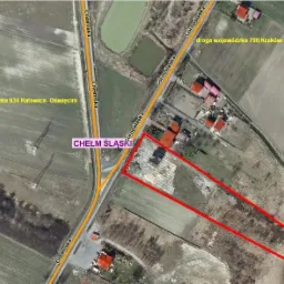 Zdjęcie satelitarne Chełmu Śląskiego przedstawiające obszar oznaczony czerwoną linią, prawdopodobnie działka budowlana z rozpoczętą budową, widoczne drogi wojewódzkie 934 i 780 oraz zabudowania...