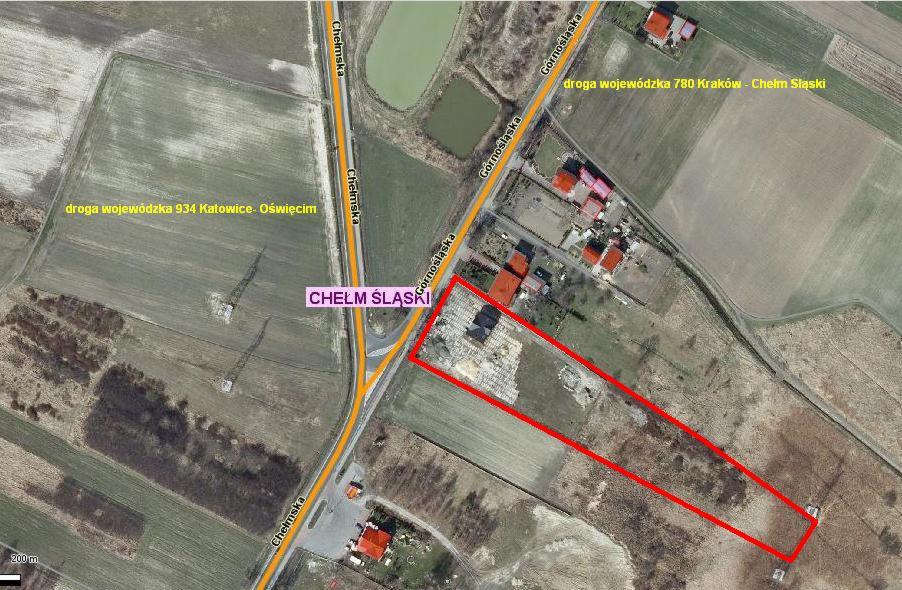 Zdjęcie satelitarne Chełmu Śląskiego przedstawiające obszar oznaczony czerwoną linią, prawdopodobnie działka budowlana z rozpoczętą budową, widoczne drogi wojewódzkie 934 i 780 oraz zabudowania...