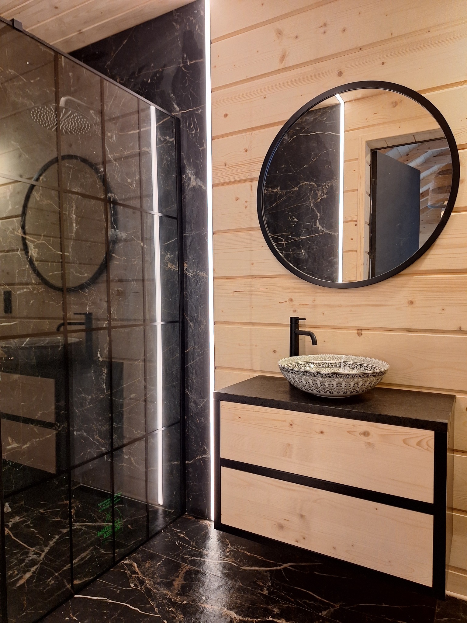 Nowoczesna łazienka z kabiną prysznicową typu walk-in, umywalką nablatową z wzorami i drewnianą boazerią.