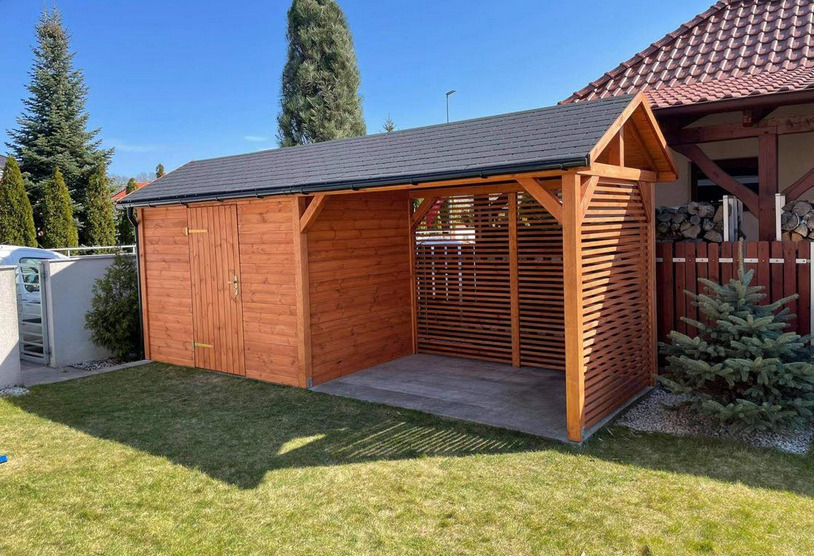 Drewniana altana z zamykaną częścią magazynową i otwartą przestrzenią z poziomymi listwami, na betonowej wylewce, otoczona trawnikiem.