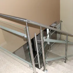 Szklana balustrada ze stali nierdzewnej na schodach wewnątrz budynku, z poziomymi pasami matowego szkła, widok z góry.