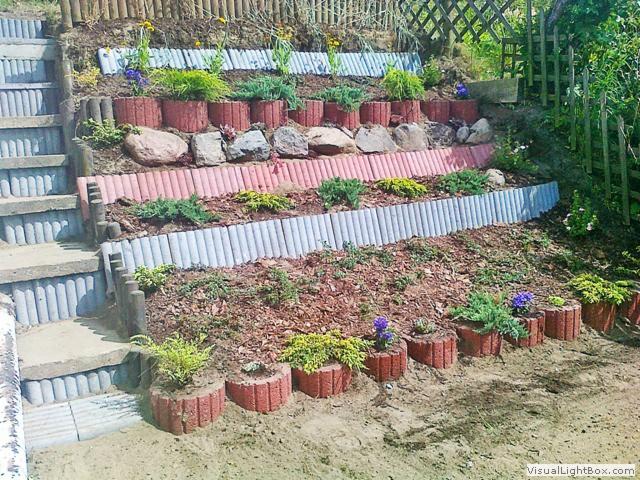 Kaskadowy ogród z betonowymi schodami i rabatami, obrzeża z rurek i kamieni. Różnorodne rośliny w donicach i na rabatach. Kompozycja nasadzeń na zboczu.