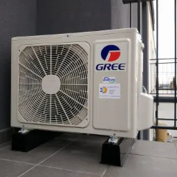 Zewnętrzna jednostka klimatyzacji Gree zamontowana na balkonie, widoczna naklejka z danymi kontaktowymi firmy instalacyjnej.