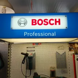 Ekspozycja elektronarzędzi Bosch Professional na perforowanej ścianie w sklepie, widoczna szlifierka kątowa i strug elektryczny wraz z cenami.