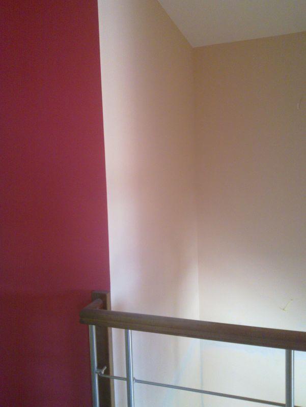 Ściana pomalowana na dwa kolory: bordowy i beżowy, z widoczną balustradą. Kontrast barw podkreśla świeżość malowania, a drewniany element balustrady dodaje ciepła.