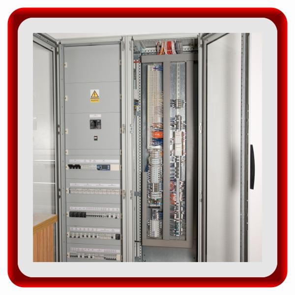 Otwarta szafa elektryczna z widocznym okablowaniem, zabezpieczeniami i elementami sterującymi. Szara obudowa, precyzyjny układ przewodów, tabliczka ostrzegawcza.