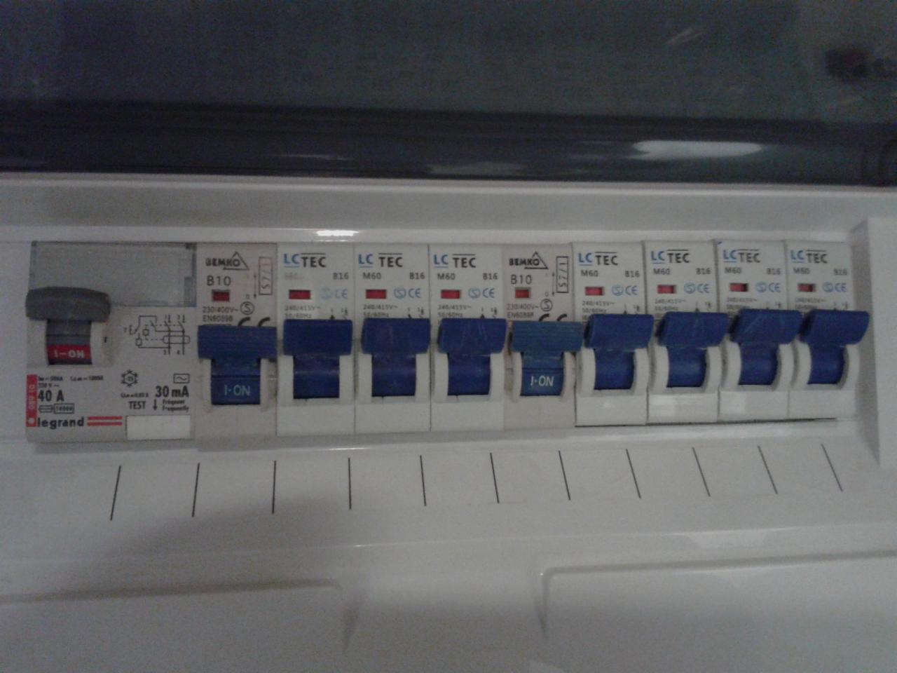 Szczegółowe ujęcie rozdzielnicy elektrycznej z wyłącznikami nadprądowymi i różnicowoprądowymi, marki Legrand i LC TEC, z dźwigniami w pozycji 'I-ON'.