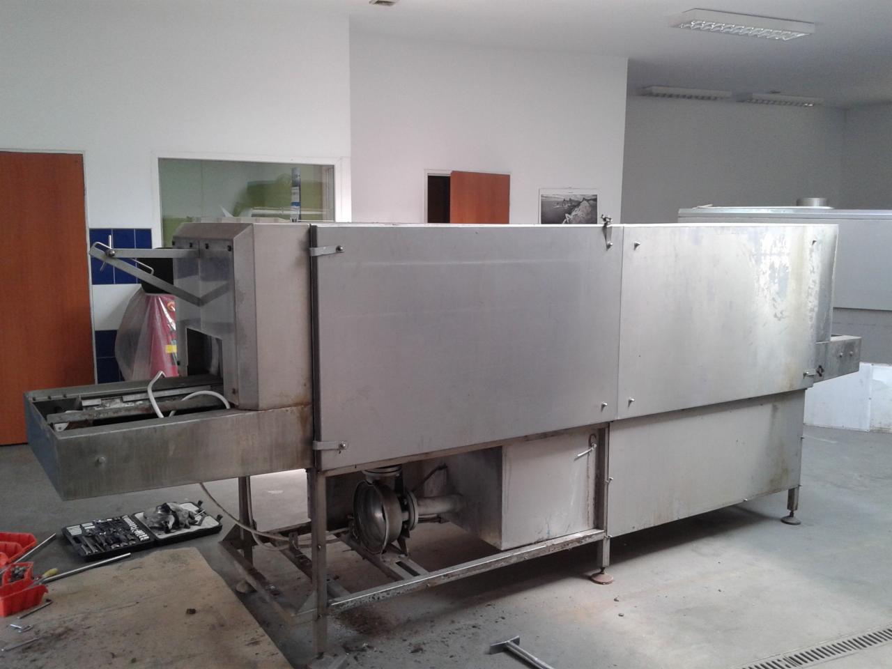 Serwis przemysłowej zmywarki tunelowej w Olsztynie. Widoczne narzędzia i elementy konstrukcyjne, sugerujące prace naprawcze lub konserwacyjne.