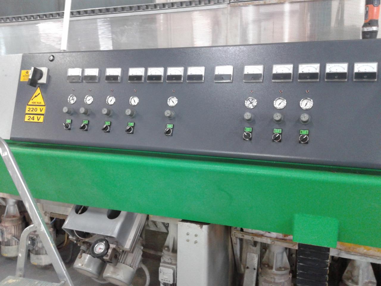 Panel sterowania szlifierki do kamienia z włącznikami, wskaźnikami i oznaczeniem napięcia 220V/24V. Widoczne silniki i elementy mechaniczne maszyny.