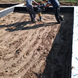 Zasypanie i ubijanie ziemi pod chudy beton.