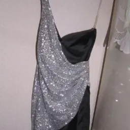 Czarno-srebrna, cekinowa sukienka mini na wieszaku, z asymetrycznym dekoltem i datą 09/05/2015 w prawym dolnym rogu, sugerująca użycie.