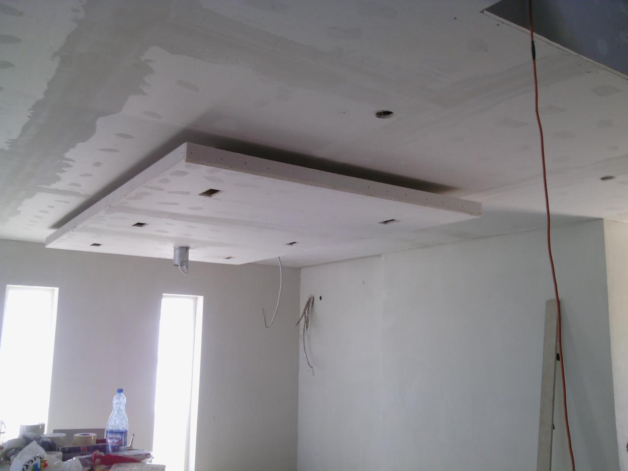 Sufit podwieszany z płyt gipsowo-kartonowych w trakcie montażu. Widoczne otwory na oświetlenie i przewody. Ściany przygotowane do malowania.
