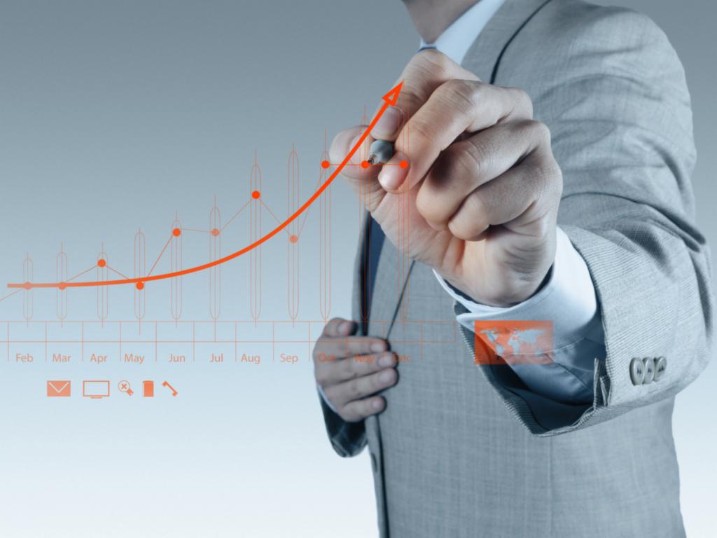 Mężczyzna w garniturze rysuje rosnący wykres na interaktywnym ekranie, symbolizujący wzrost w kampaniach reklamowych.