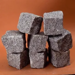 Stos ułożonych, surowych, szarych bloków granitowych na jednolitym, brązowym tle.