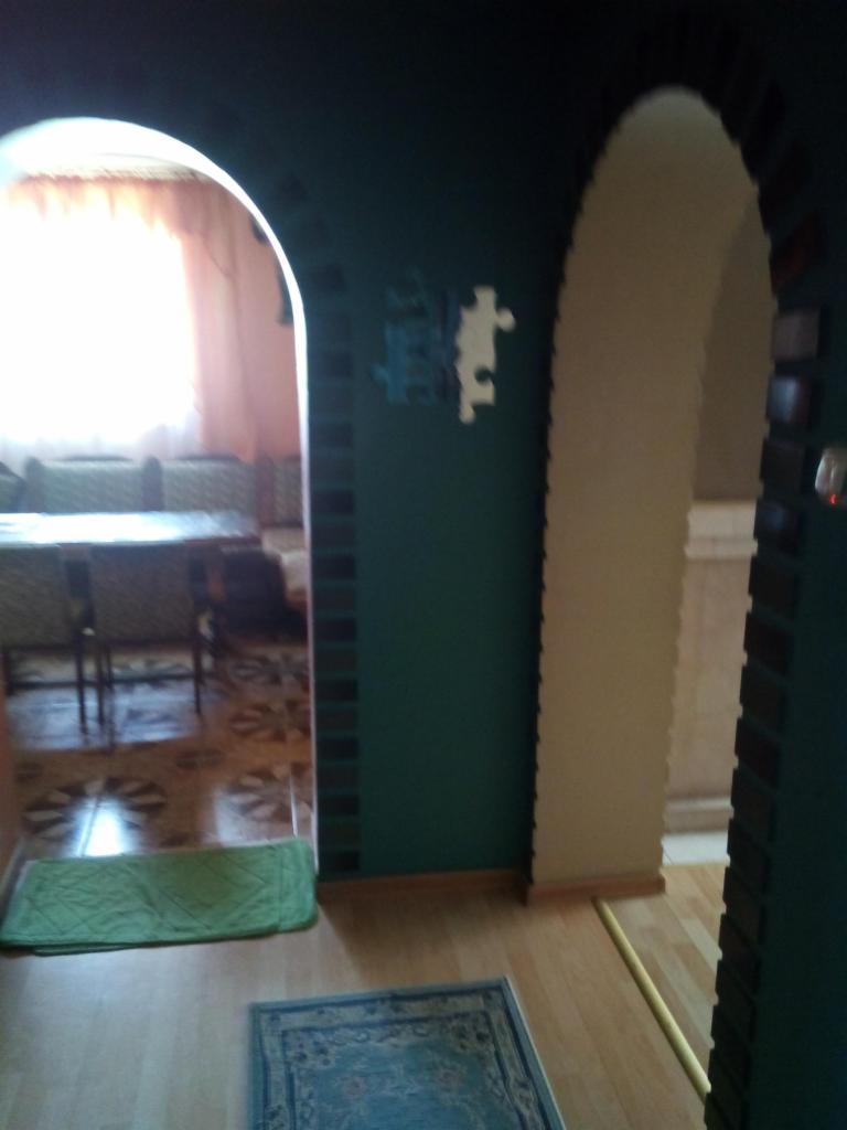 Wnętrze z dwoma łukowatymi przejściami pomalowanymi na różne kolory, dekoracją w postaci puzzli na ścianie i dywanami na podłodze.