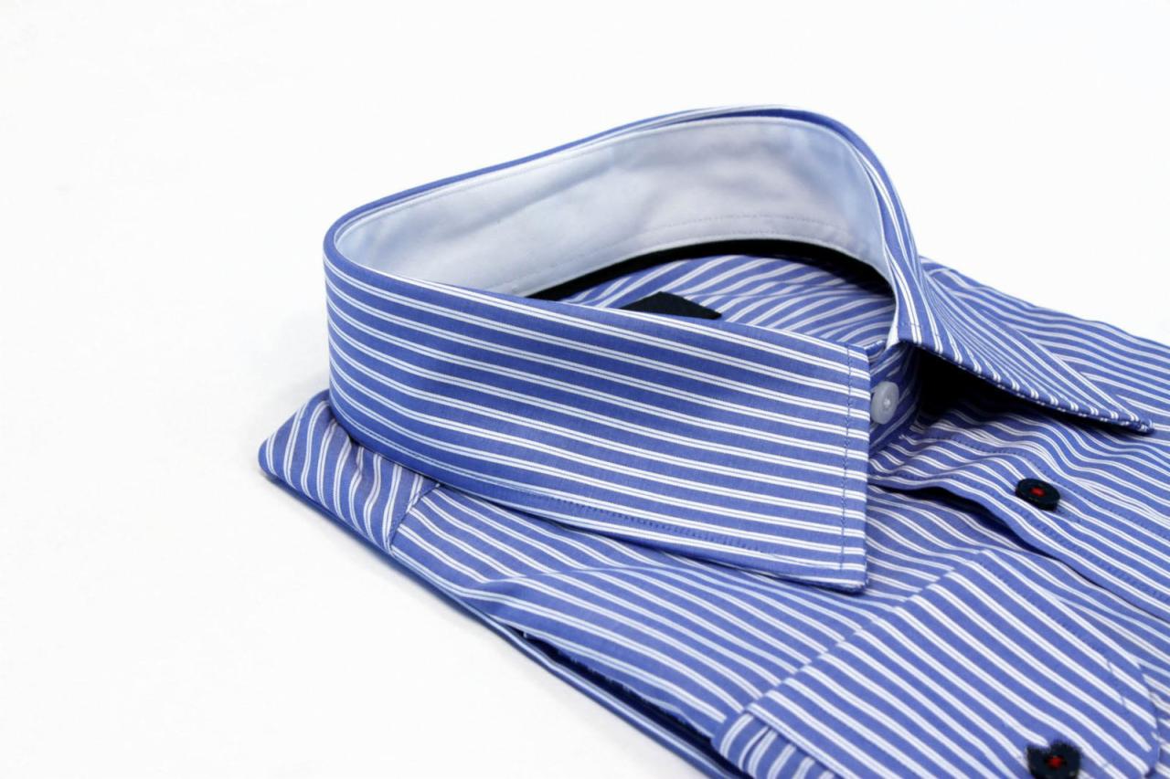 Złożona, niebieska koszula męska w białe paski, z widocznym kołnierzykiem i mankietami na białym tle.