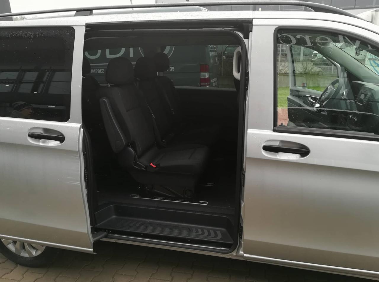 Wnętrze srebrnego vana z otwartymi drzwiami przesuwnymi, widoczne czarne fotele z pasami bezpieczeństwa i gumowa podłoga.