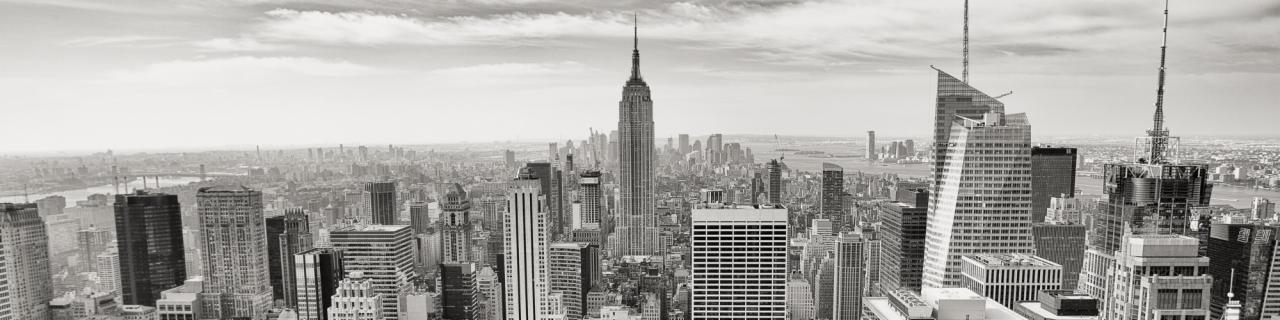 Czarno-biała panorama Manhattanu z bliska, zarys Empire State Building, budynki o zróżnicowanej architekturze i delikatna mgła w tle. Ujęcie z góry.