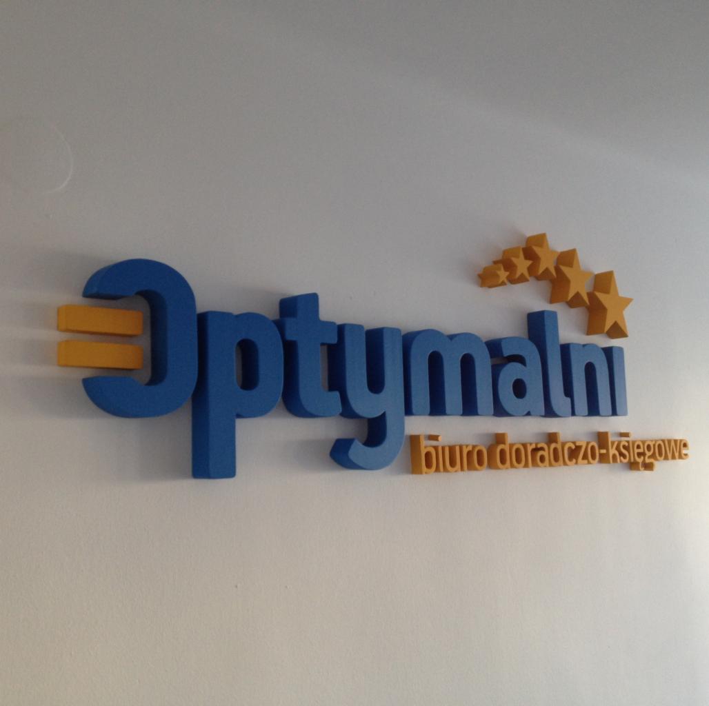 Logo 'Optymalni biuro doradczo-księgowe' na białej ścianie. Niebieskie, przestrzenne litery i pomarańczowe akcenty graficzne tworzą nowoczesny, profesjonalny wizerunek.