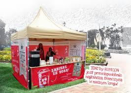 Namiot handlowy z wyposażeniem franczyzowym w Czyżowicach, z widocznym stoiskiem do serwowania napojów i przekąsek, udekorowany czerwonymi banerami z logo i hasłami reklamowymi.