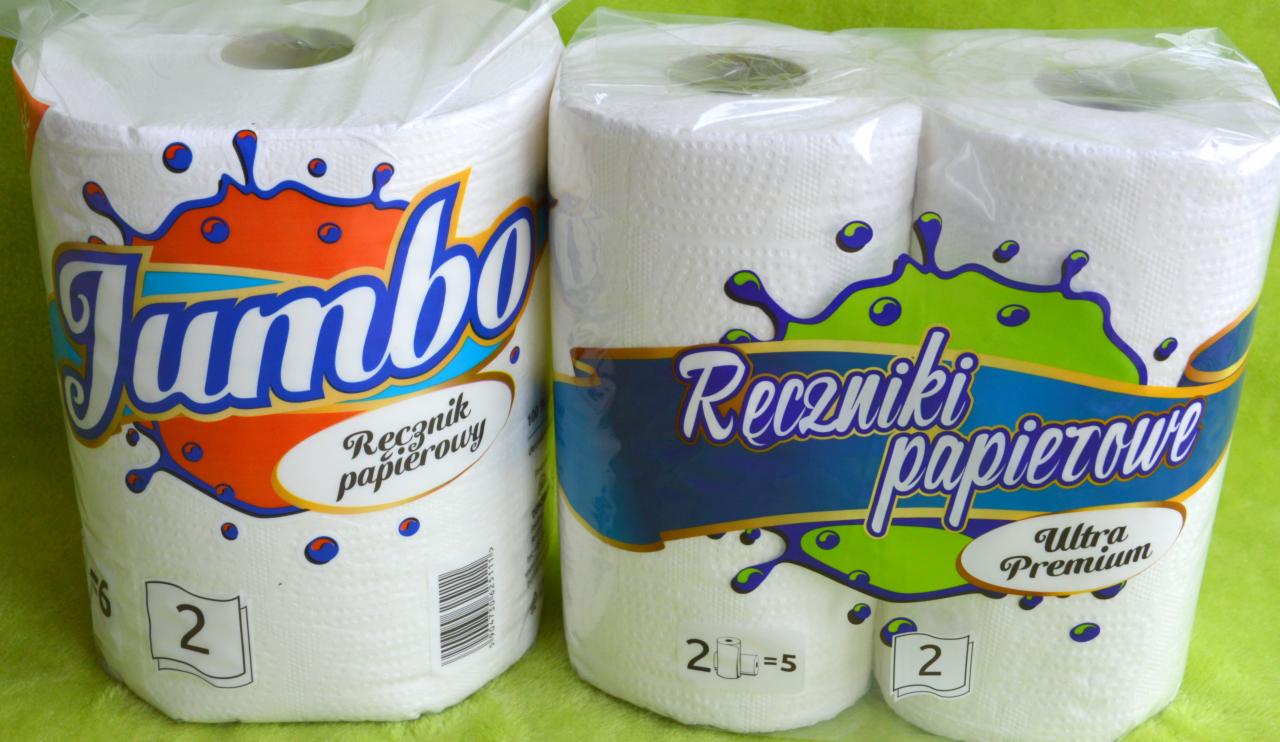 Dwa opakowania ręczników papierowych: Jumbo w pomarańczowo-niebieskim opakowaniu i Ultra Premium w niebiesko-zielonym, na zielonym tle.