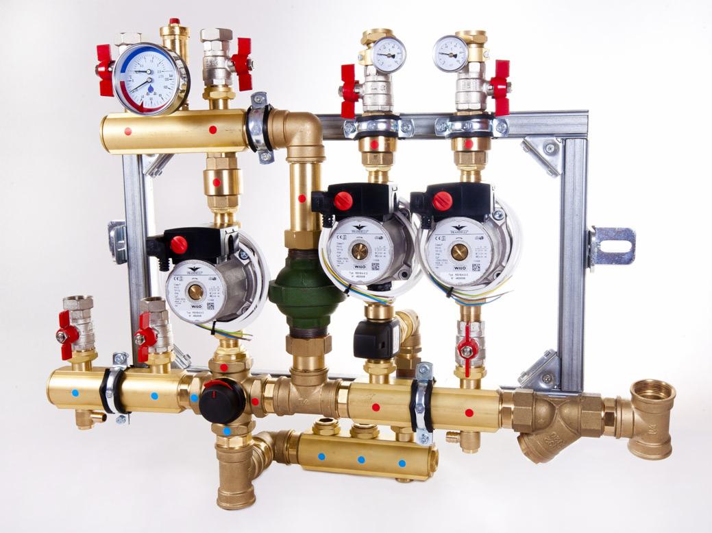 Kompaktowa, złoto-mosiężna instalacja CO z manometrami, pompami obiegowymi Wilo i zaworami z czerwonymi kurkami, zamontowana na srebrnej ramie na białym tle.