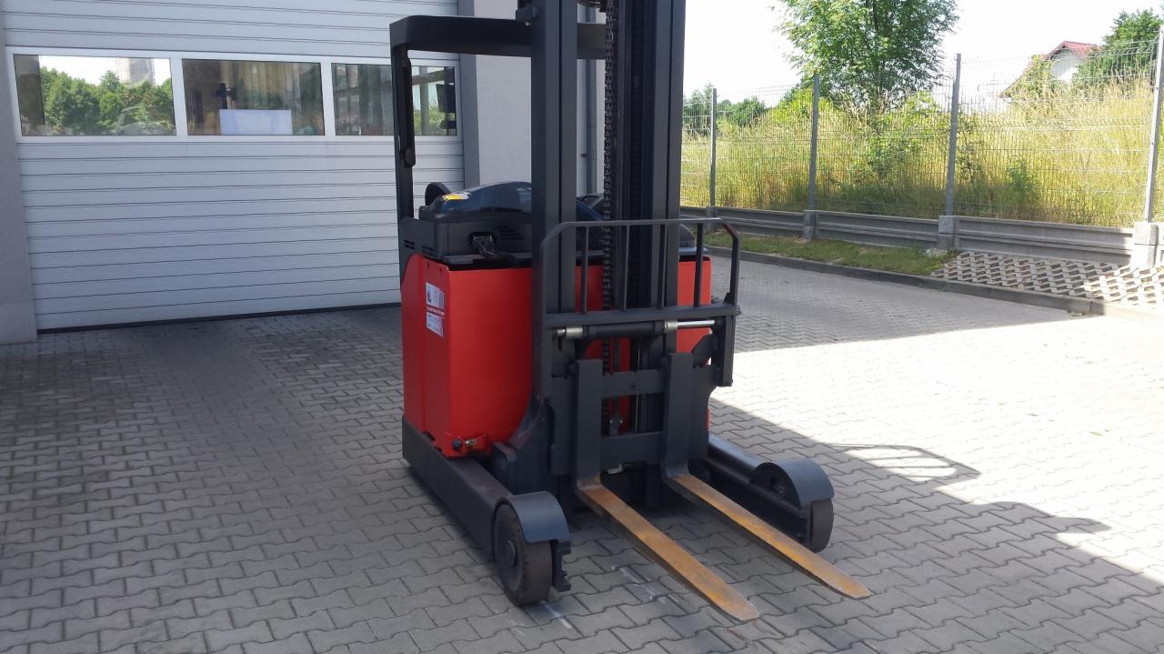 Czerwono-czarny wózek widłowy wysokiego składowania Linde R16 stoi na kostce brukowej przed szarą bramą garażową i ogrodzeniem z siatki.