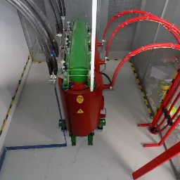 Widok z góry na zainstalowany transformator energetyczny w pomieszczeniu z kablami i oznaczeniami bezpieczeństwa, prezentujący profesjonalny montaż.