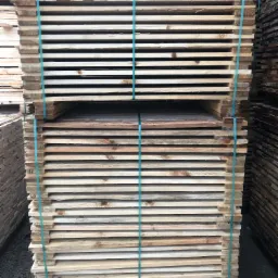 Stosy świeżo przetartego drewna budowlanego, zabezpieczone niebieską taśmą, składowane w Elblągu.