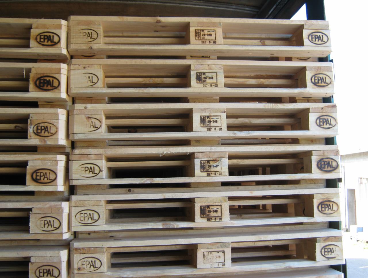 Stos drewnianych palet EPAL, widoczne oznaczenia licencyjne i numery seryjne, jasne drewno, ułożone równo w stosie, widok z bliska, oświetlenie dzienne.