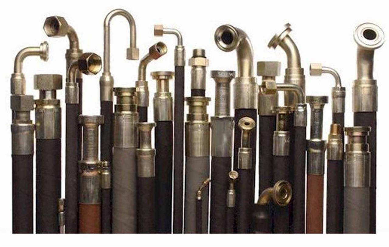 Zestaw nowych, różnorodnych przewodów hydraulicznych z metalowymi końcówkami i złączkami, ustawionych pionowo na białym tle.