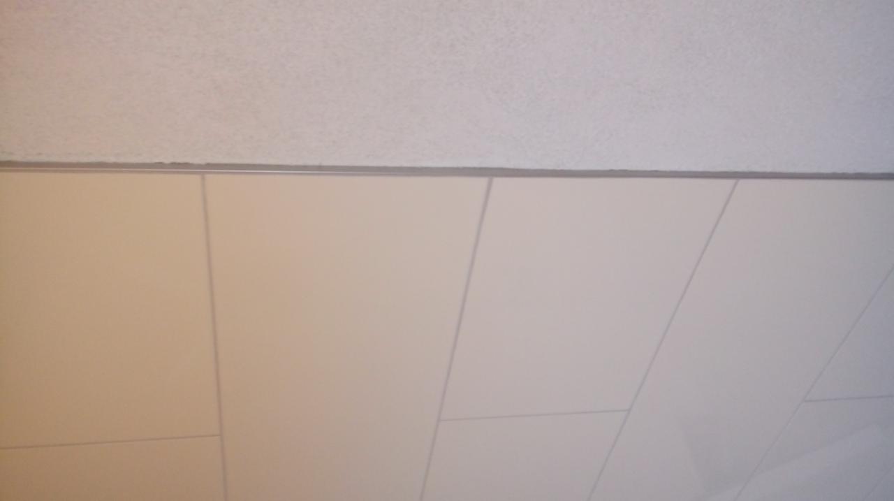 Fragment sufitu podwieszanego z białymi panelami i widoczną konstrukcją nośną.