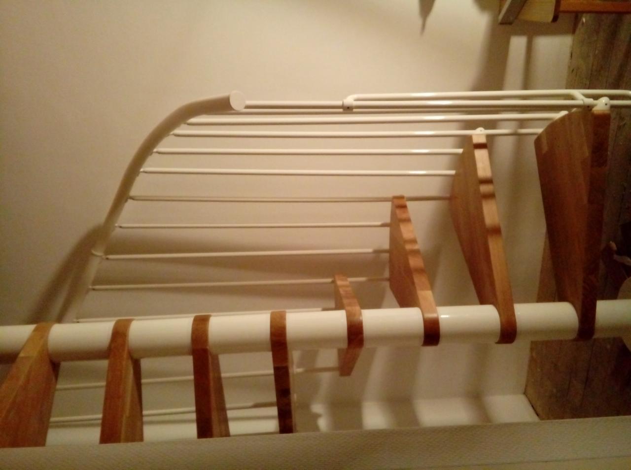 Konstrukcja schodów z drewnianymi stopniami, białe metalowe barierki, widok z dołu.