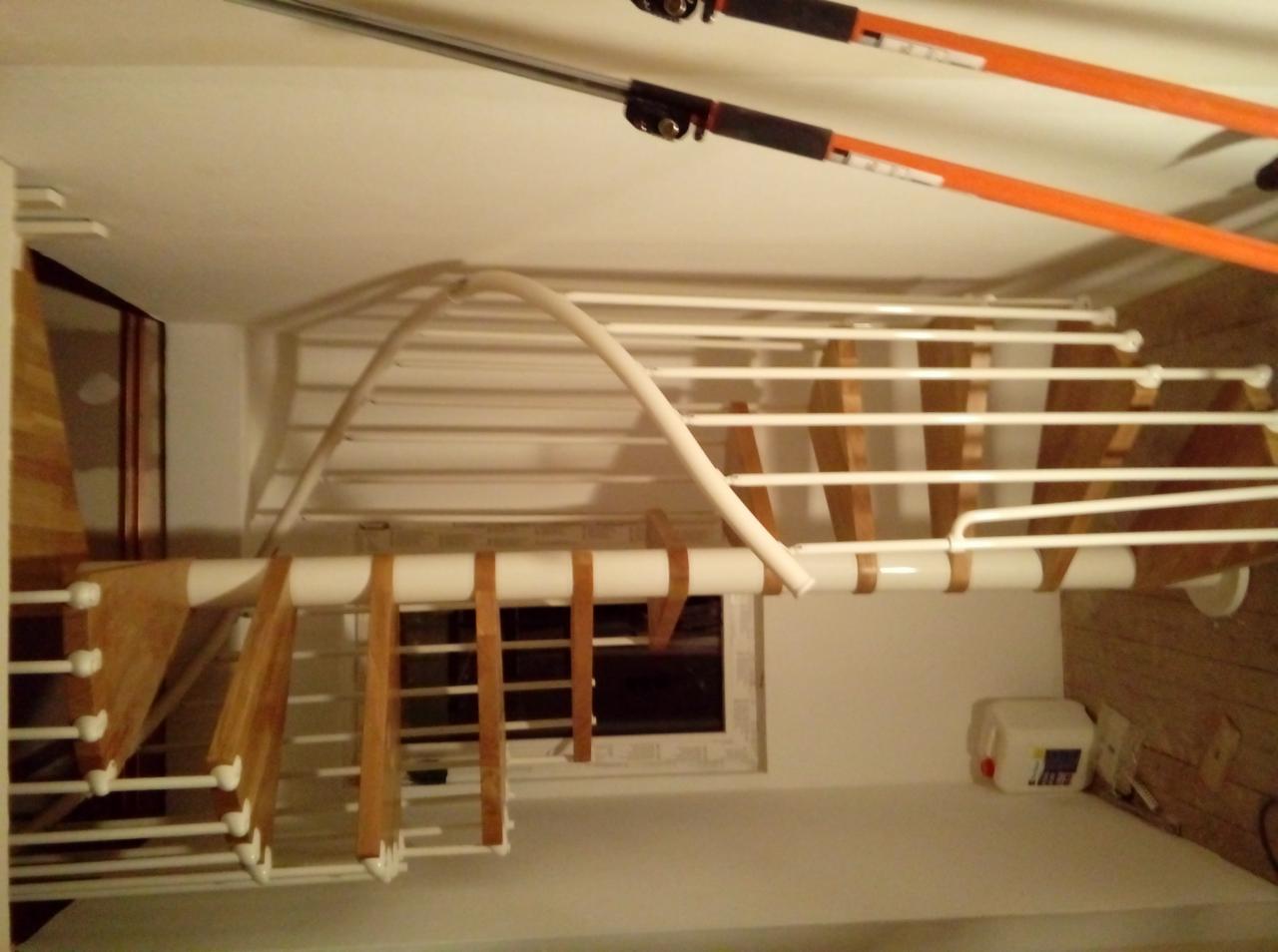 Nietypowy widok suszarki sufitowej z drewnianymi elementami, zamontowanej w pomieszczeniu z oknem, widoczne narzędzia teleskopowe do opuszczania suszarki.