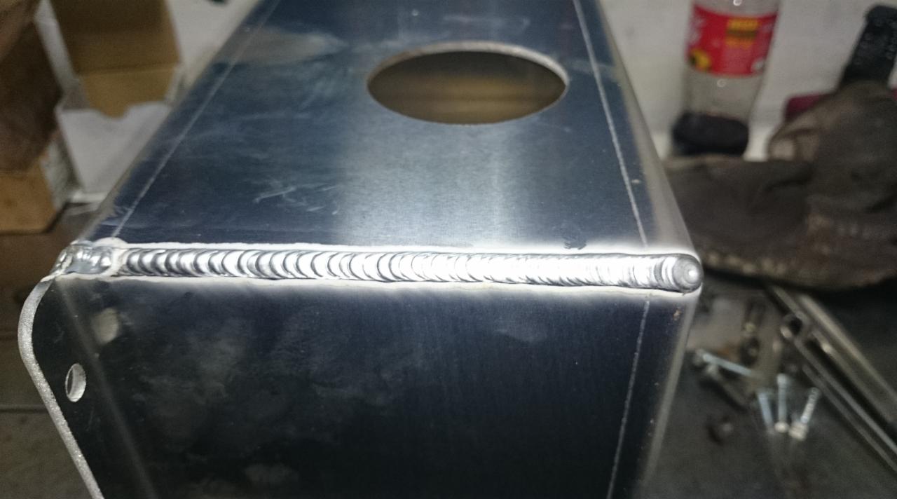 Metalowa konstrukcja po spawaniu z widocznym spoiną, otworem i elementem mocującym, ukazana z bliska.